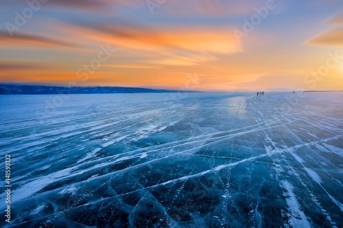 Beautiful view of cracked ice of a frozen lake Baikal during sunrise.