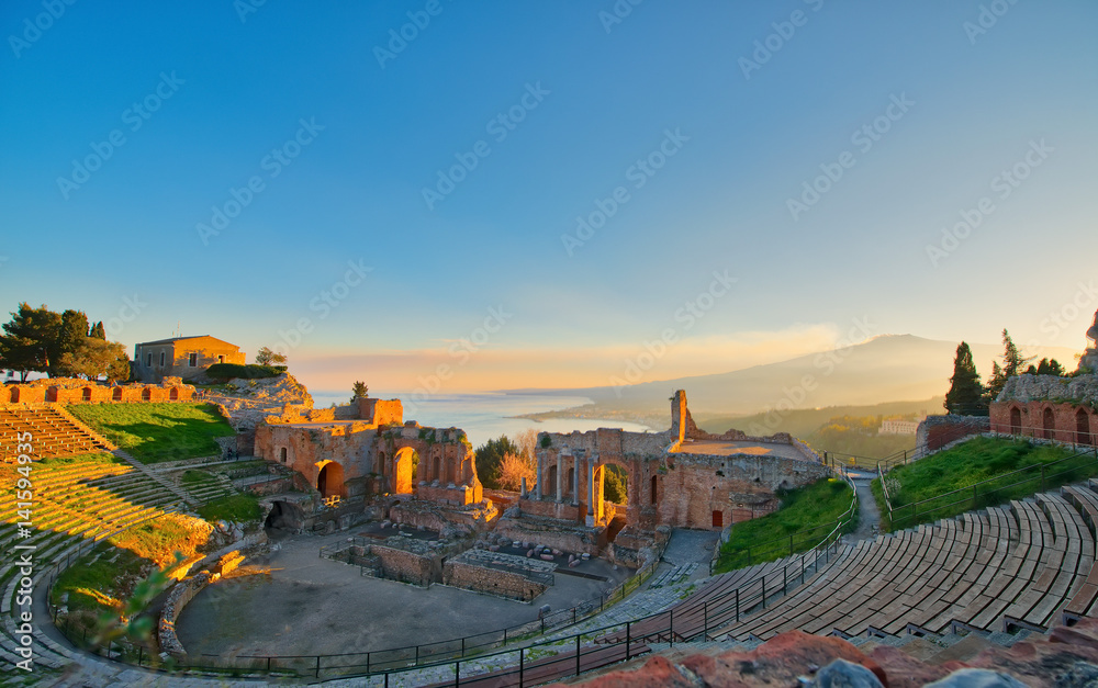 Obraz premium Ancient theatre of Taormina with Etna erupting volcano at sunset