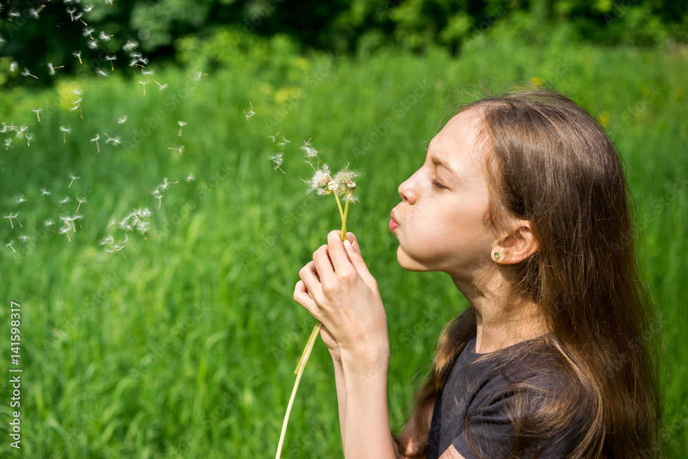 Young girl in the park blowing on dandelion Young girl in the park blowing on dandelion