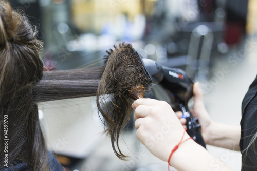 Drying brunette hair with hair dryer and round brush,close up