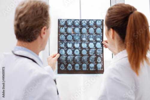 Focused doctors holding MRI scans against the light