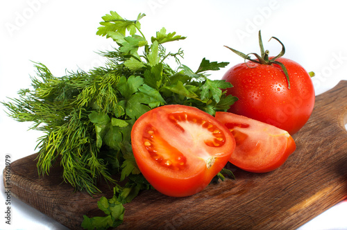 Red tomatoes with parsley on a wooden board