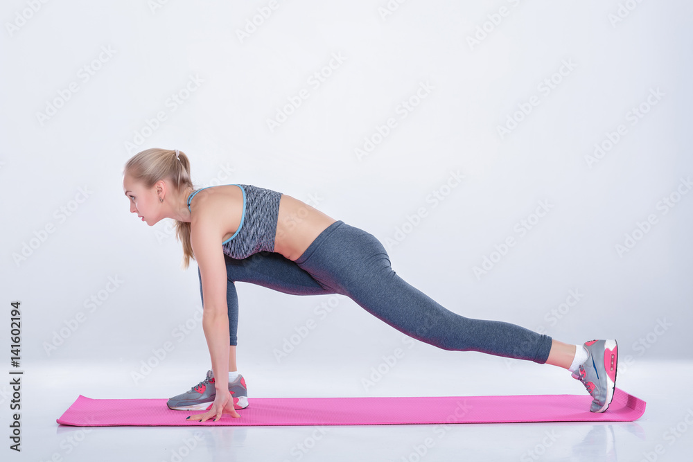 beautiful blonde woman does exercises on fitness Mat on gray background. stretching beautiful blonde woman does exercises on fitness Mat on gray background. stretching