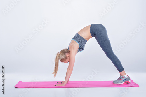 beautiful blonde girl in sportswear does exercises on fitness Mat. woman practicing yoga