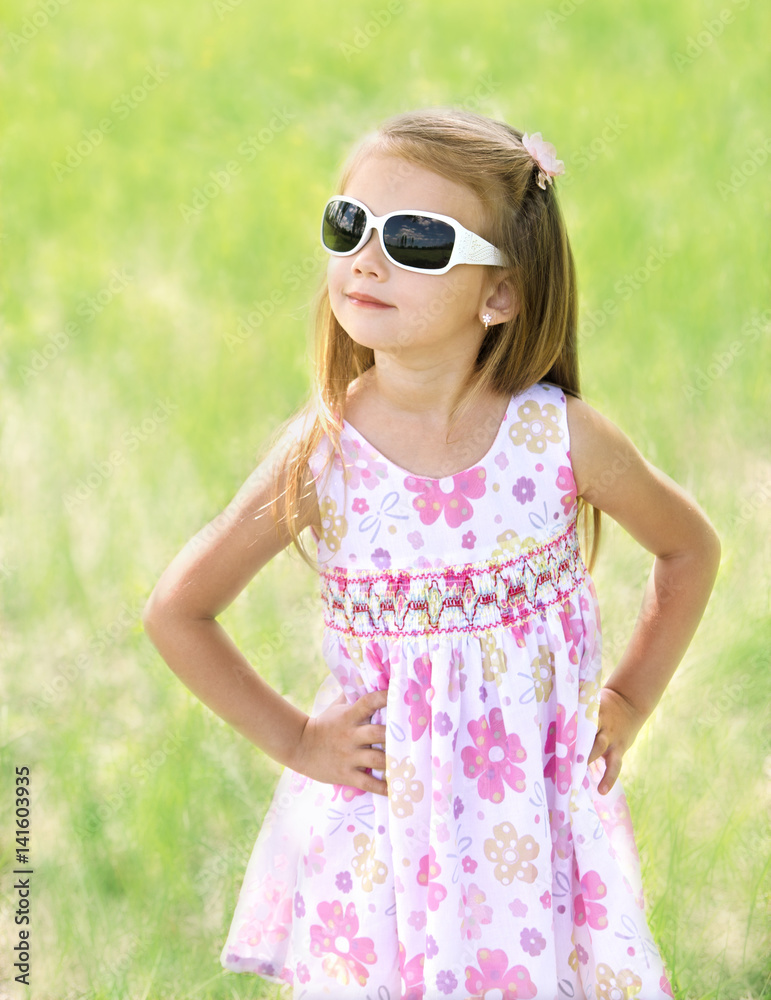 Cute smiling little girl in sunglasses on the meadow Cute smiling little girl in sunglasses on the meadow
