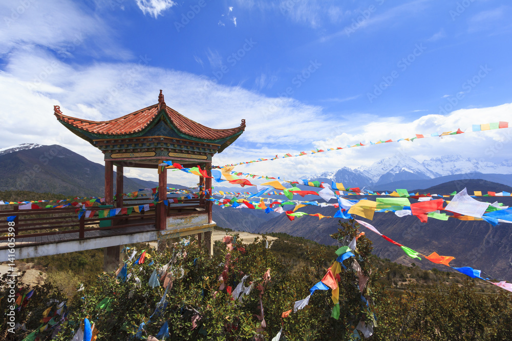Fototapeta premium Meili snow mountain with Prayer flags and Chinese style roof, Deqing, Yunnan, China