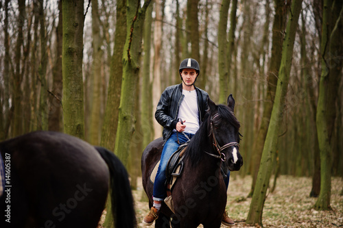 Young stylish man riding on horses at autumn forest.