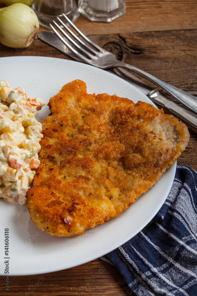 Fried pork chop in breadcrumbs, served with vegetable salad. Fried pork chop in breadcrumbs, served with vegetable salad.