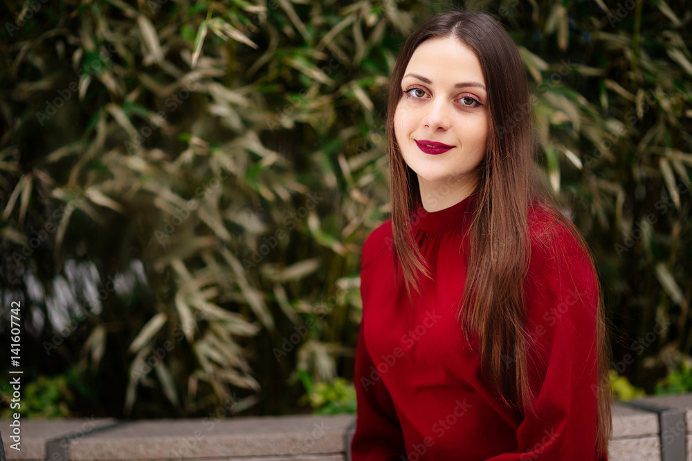 Young woman sitting on the bench and smilling to camera Young woman sitting on the bench and smilling to camera