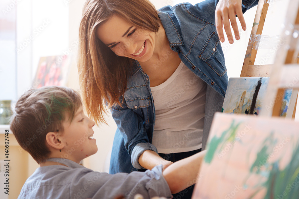 Charming young artist teaching painting kid at school Charming young artist teaching painting kid at school