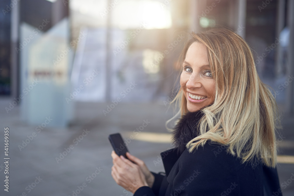 Lächelnde blonde Geschäftsfrau mit ihrem Handy Lächelnde blonde Geschäftsfrau mit ihrem Handy