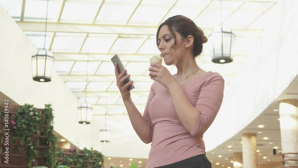 Attractive young woman sends message on mobile phone and eats ice cream Attractive young woman sends message on mobile phone and eats ice cream
