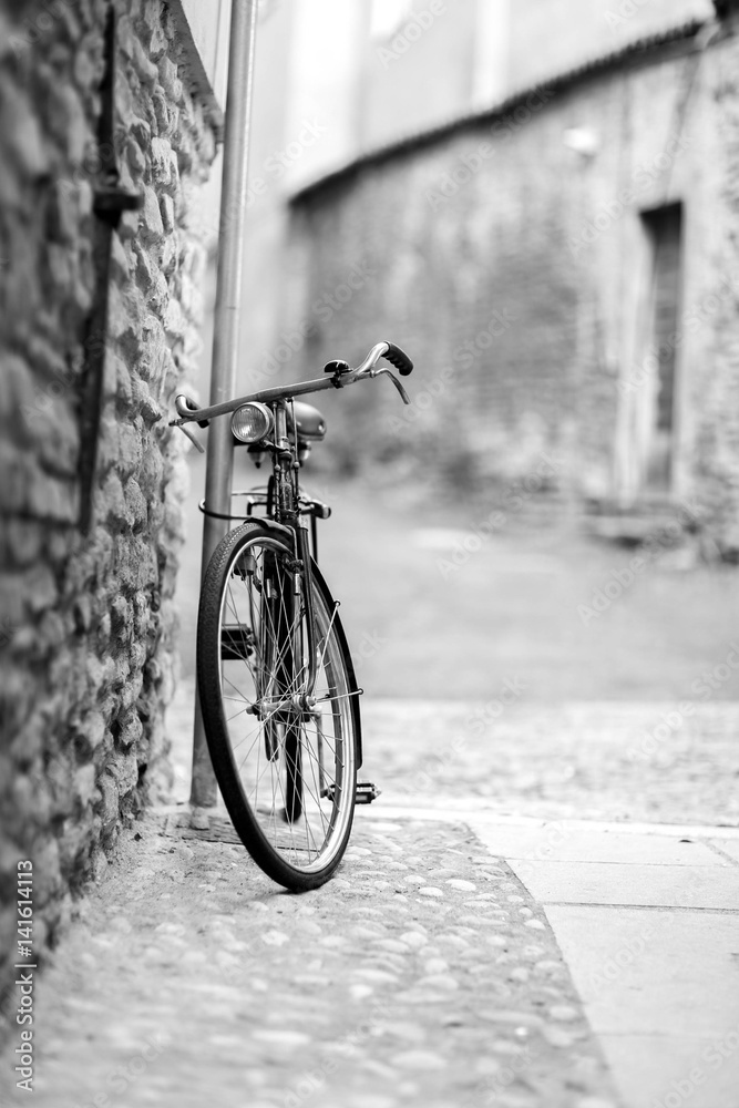 Black and white photo of lonely old bicycle near the stone wall