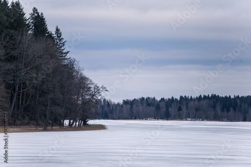 A peaceful winter landscape with a frozen lake in overcast day
