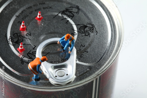 The miniature figure model of worker on aluminum can lid represent the food packaging business concept related idea.