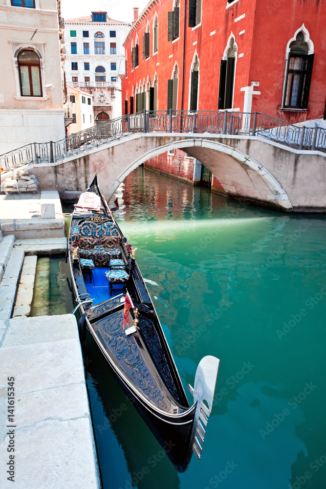 Gondola on Venice canal with bridge and houses standing in water
