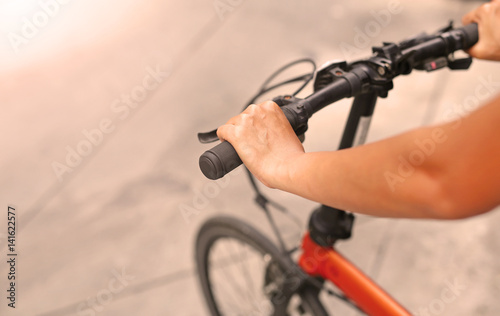 Woman riding a bicycle. Closeup on handlebar with female hand. Healthy lifestyle and sport concept