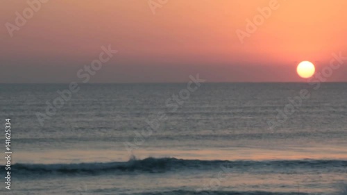 Early  Morning sun rising over ocean with bird flying across