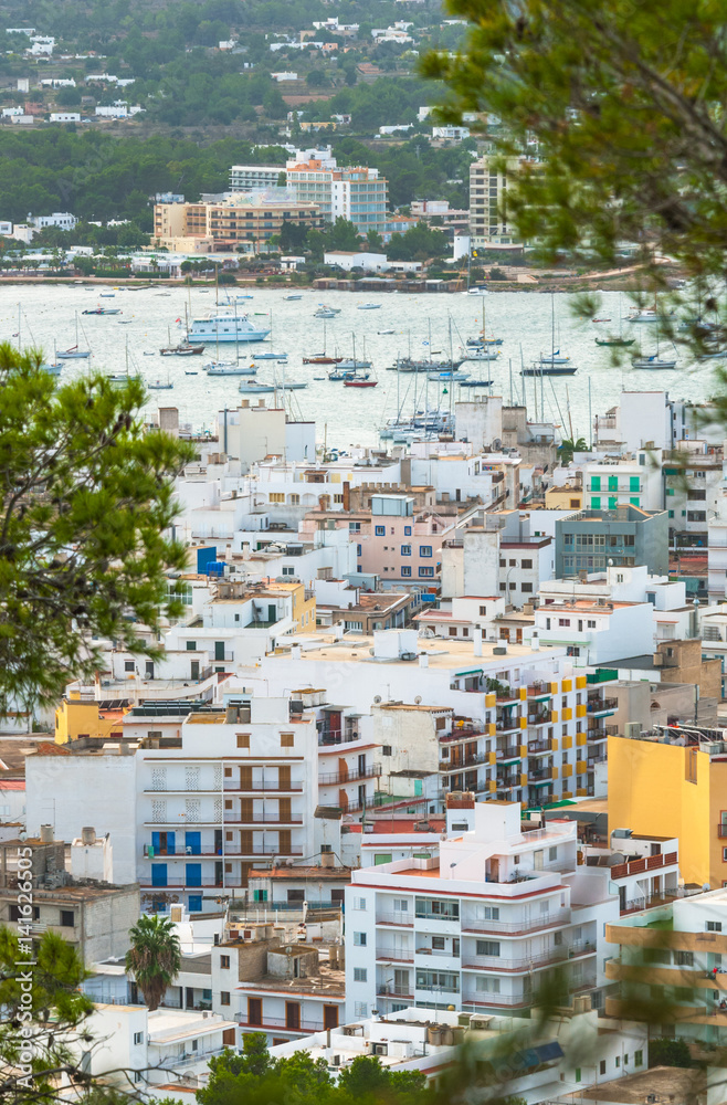 Views through the trees from hillside nearby, into St Antoni de Portmany Balearic Islands, Ibiza, Spain.