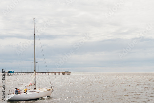 Sailboat sailing on the Rio de la Plata, Argentina, with pier on background