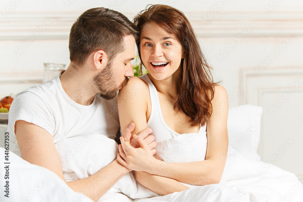 Fototapeta premium Young adult heterosexual couple lying on bed in bedroom