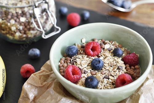 Delicious cereal breakfast with bowl and fresh fruits. Fresh blueberry and raspberry fruits, healthy eating scene.
