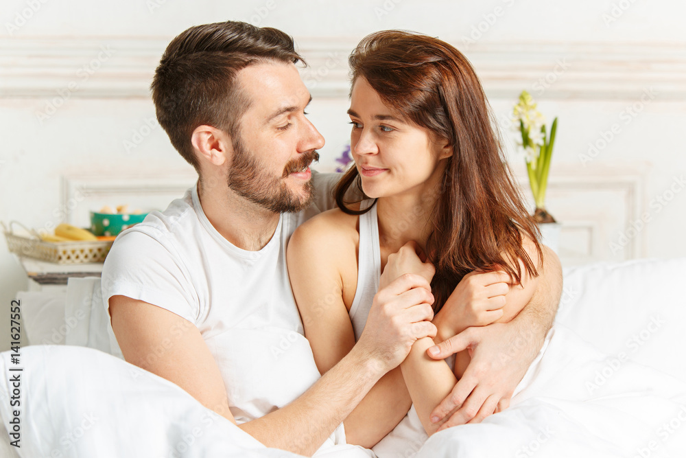 Young adult heterosexual couple lying on bed in bedroom Young adult heterosexual couple lying on bed in bedroom