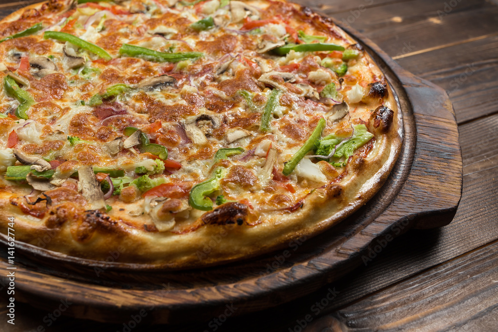 Delicious pizza with mushrooms - thin pastry crust isolated at wooden background on wooden desk