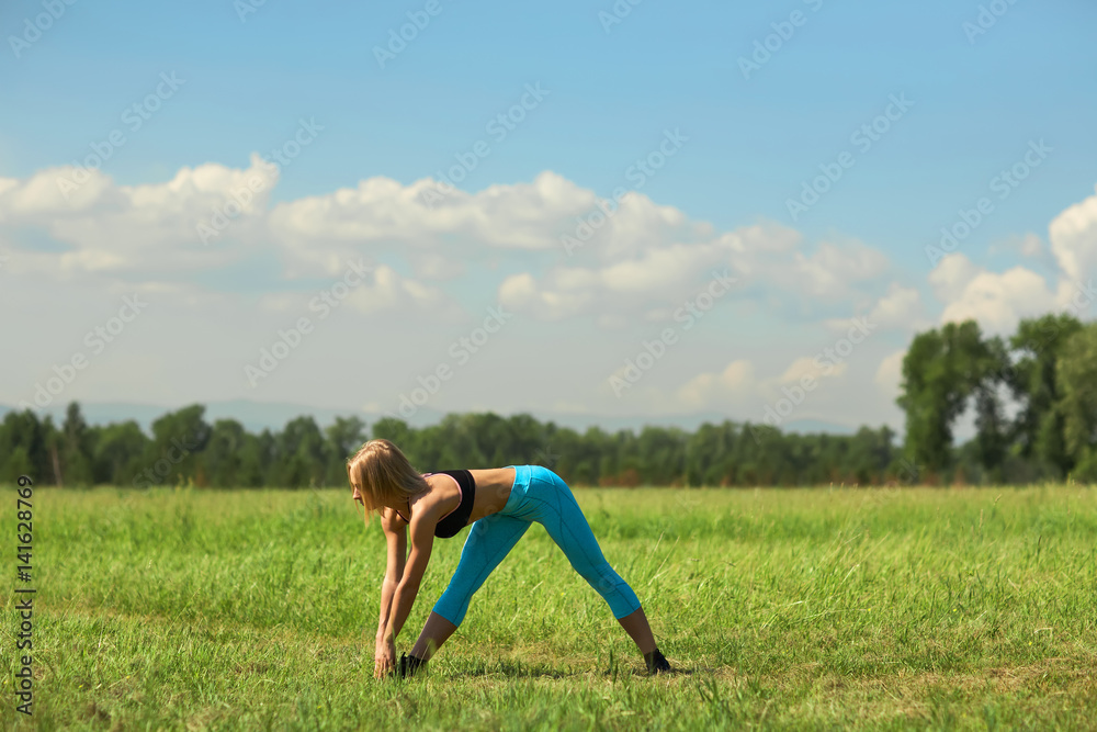 Beautiful sport woman doing stretching fitness exercise in city park at green grass. Yoga postures Beautiful sport woman doing stretching fitness exercise in city park at green grass. Yoga postures