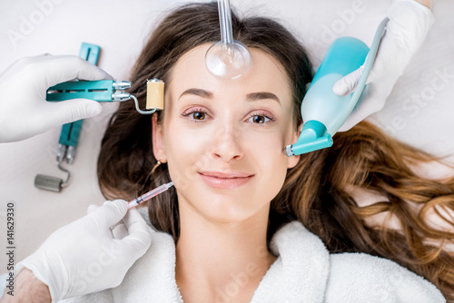 Beautiful woman with cosmetology tools lying on the medical couch. Facial treatment concept photo