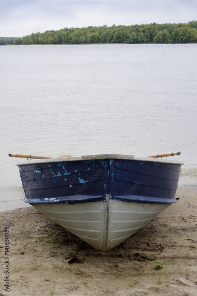 Obraz premium rustic blue boat on beach at river