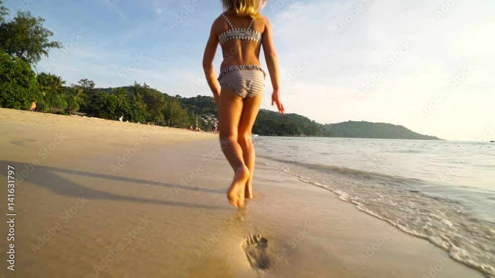 Little cute funny girl laughing and running on the beach