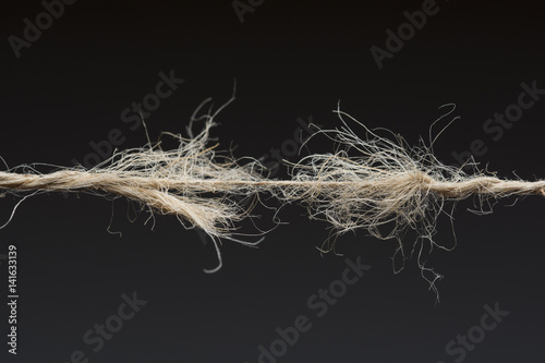 Frayed rope ready to break on dark background photo