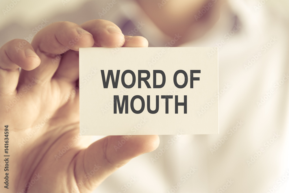 Businessman holding WORD OF MOUTH message card Businessman holding WORD OF MOUTH message card