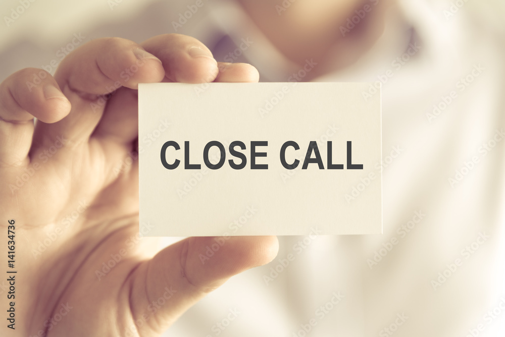 Businessman holding CLOSE CALL message card Businessman holding CLOSE CALL message card