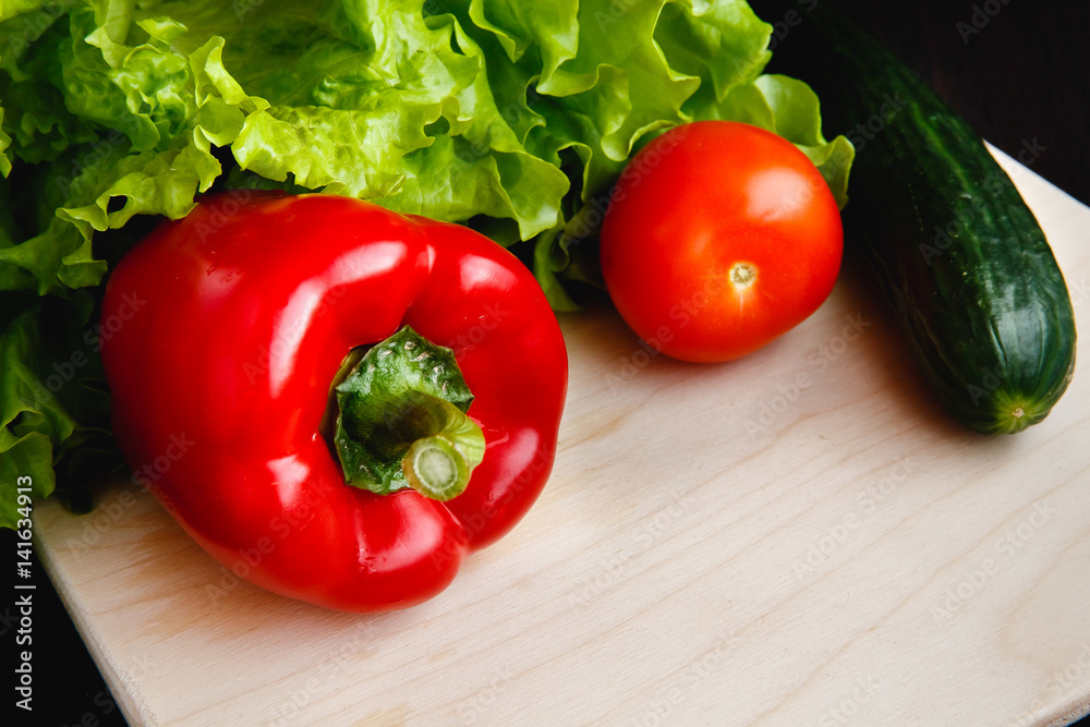 Fresh vegetables on the table: red pepper, lettuce, cucumber, tomatoes. Cutting board Fresh vegetables on the table: red pepper, lettuce, cucumber, tomatoes. Cutting board