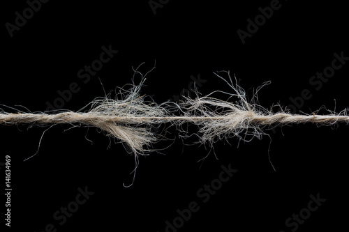 Frayed rope ready to break isolated on black background