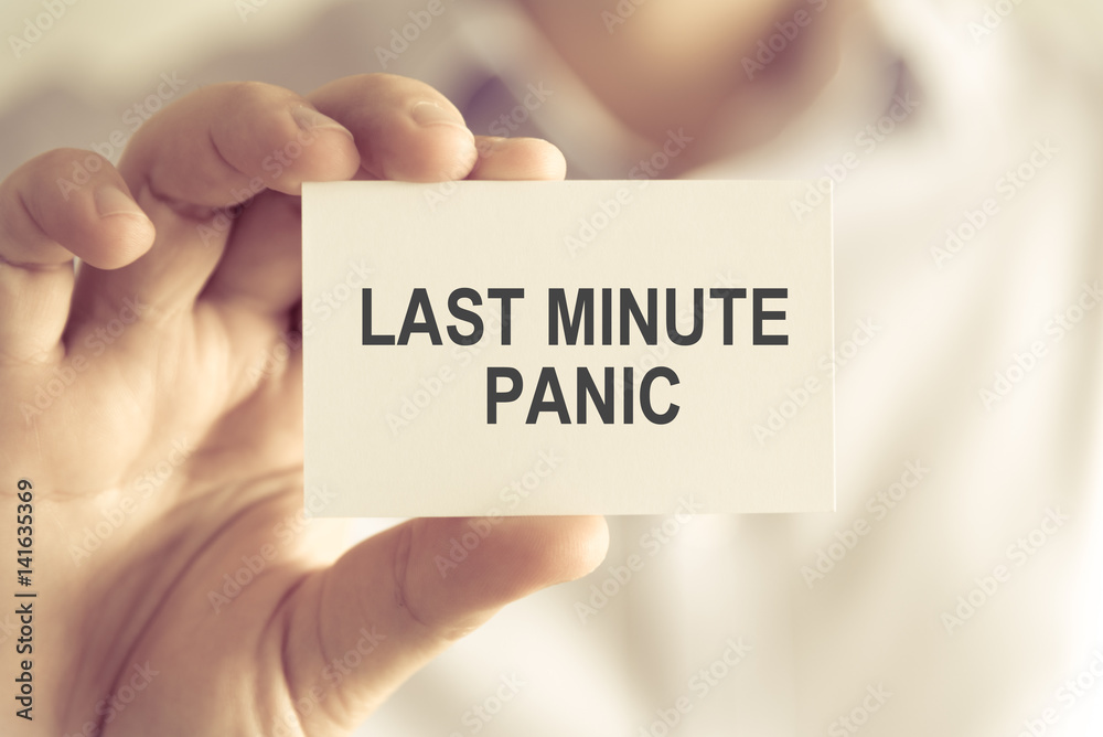 Businessman holding LAST MINUTE PANIC message card Businessman holding LAST MINUTE PANIC message card