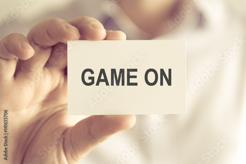 Businessman holding GAME ON message card