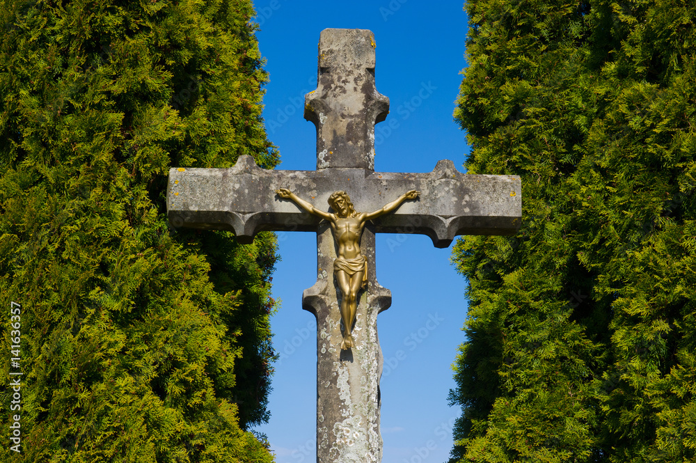 golden jesus statue on a crucifix between two trees golden jesus statue on a crucifix between two trees