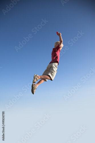 Blonde young boy jump high up