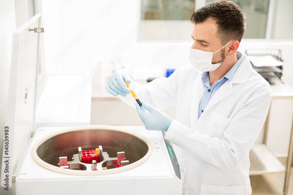 Male chemist working with a centrifuge Male chemist working with a centrifuge