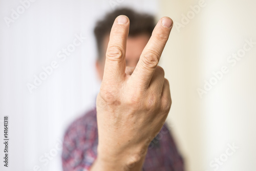 Mann zeigt zwei Finger am ausgestreckten Arm © bevisphoto