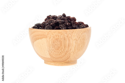 Dried raisins in wooden cup on white background.