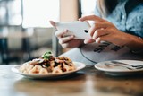 Hands of woman taking a photo of breakfast with smartphone.