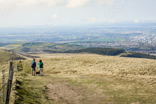 Couple and a dog walking on the top of the hill