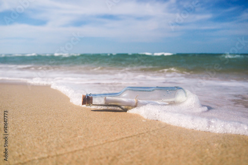 Message in a bottle on beautiful beach with waves.