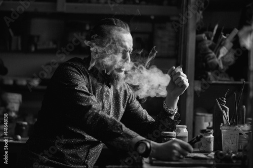 Man portrait smoking an electronic cigarette in art studio