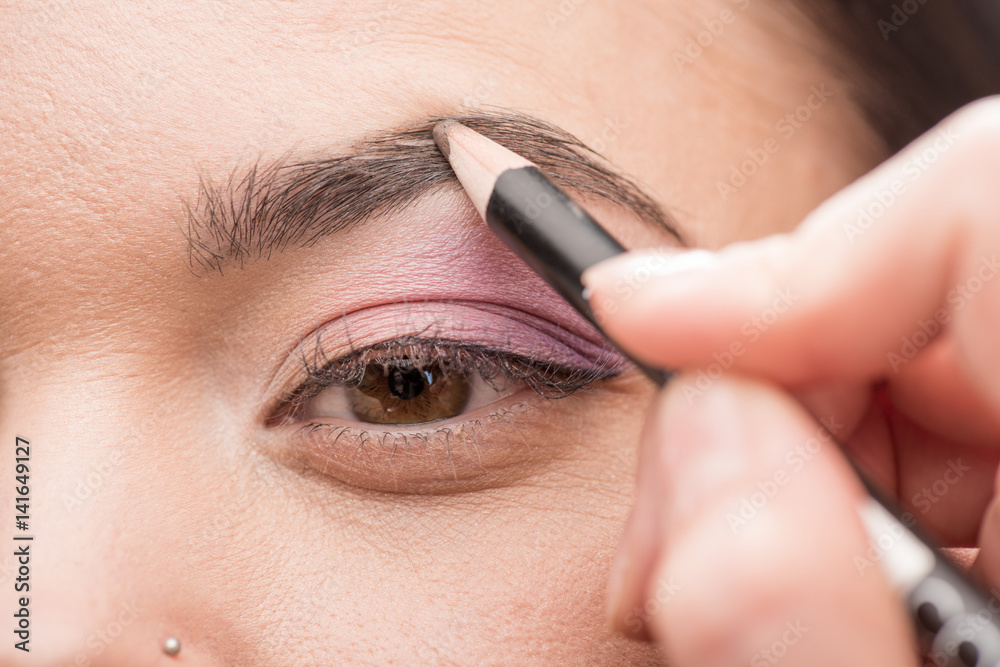 Woman drawing a shape of eyebrow