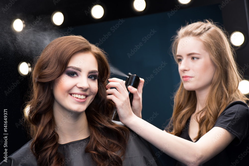 Hairdresser fixing hair of model